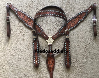 May include: A brown leather horse bridle with turquoise stitching and floral tooling. The bridle includes a browband, reins, and a throatlatch.