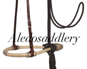 May include: A brown leather halter with a braided rawhide noseband and a black rope lead rope with a tassel. The halter is attached to the lead rope.