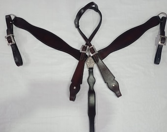Puede incluir: Un collar de pecho de cuero marrón para caballo con hebillas plateadas y detalles decorativos. El collar tiene tres correas que se conectan a las hebillas.