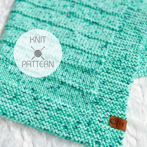 May include: A teal blue knitted blanket with a white label that says "Knit Pattern".