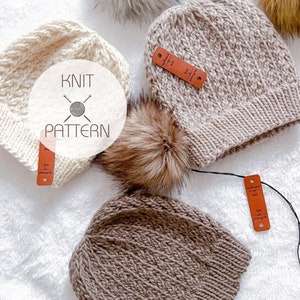 Könnte beinhalten: Zwei Strickmützen mit Bommeln. Eine Mütze ist beige und die andere ist weiß. Beide Mützen haben ein Strickmuster und sind aus weichem Garn gefertigt. Die Mützen liegen auf einer weißen Oberfläche mit einem Etikett, auf dem "Knit Pattern" steht.