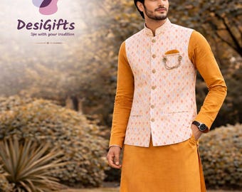Può includere: Un uomo indossa un kurta color senape e un gilet fantasia, abbinato a pantaloni da pigiama bianchi e mocassini marroni. L'outfit fa parte di un look etnico premium. È visibile il logo "DesiGifts".