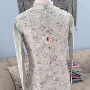 May include: A light gray long-sleeved tunic paired with a sleeveless vest featuring a complex geometric and floral pattern in shades of silver, beige, and soft pink. The vest includes a mandarin collar, five round buttons, and a small chest pocket.