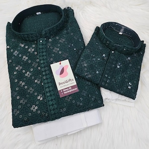 May include: Two green embroidered shirts with sequins. The larger shirt has a tag that reads "Desigifts" with the text "Care with your tradition" and a website address.