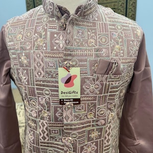 May include: A mauve-colored embroidered jacket with a mandarin collar and ornate button closures. The jacket features a detailed pattern of floral and geometric designs. A tag from DesiGifts is attached.