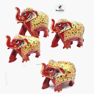 May include: Four hand-painted wooden elephants in red, gold, and green. The elephants are standing on a white surface. DesiGifts is printed on the image.