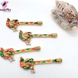 May include: Four gold peacock hair sticks with colorful enamel and pearl accents. The sticks are arranged in a row on a white background.