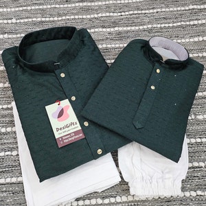 May include: Two dark green kurta shirts with white buttons and a white tag that says "DesiGifts" with a website address. The shirts are on a white fabric background.