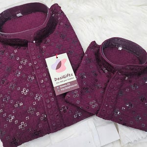May include: Two maroon kurta shirts with intricate lace detailing and a mandarin collar. The shirts are made of a soft, lightweight fabric and are perfect for special occasions.