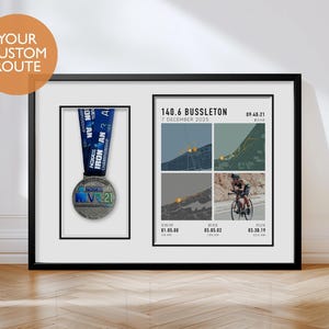 Pode incluir: Impressão emoldurada em preto com uma medalha e detalhes da corrida. A medalha prateada tem uma fita azul. A impressão inclui o texto "140.6 Busselton 7 de dezembro de 2025" e os tempos de corrida para natação, bicicleta e corrida. O canto superior esquerdo tem o texto "YOUR CUSTOM ROUTE".