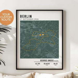 Könnte beinhalten: Ein gerahmter Kunstdruck mit einer Karte von Berlin und einer orangefarbenen Routenführung. Der Text lautet BERLIN, 27 SEPTEMBER 2026, GEORGE KNUSS #2289, 42.195 KM, 03:40:02 TIME und 04:53 /KM. Der Kartenhintergrund ist dunkelgrün mit weißen Straßen.