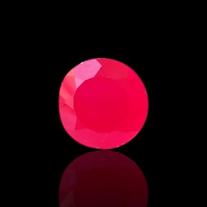 Peut inclure: Une pierre précieuse rouge vif, ronde et facettée, sur fond noir. La surface de la gemme reflète la lumière, créant un aspect brillant. La gemme est d'une teinte rouge vibrante, avec une surface polie et réfléchissante.