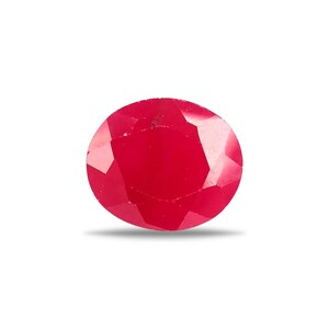 Puede incluir: Una gema de rubí de corte ovalado en color rojo intenso, con múltiples facetas geométricas que reflejan la luz. La piedra muestra una superficie pulida y translúcida con bordes definidos y una forma simétrica sobre un fondo de color blanco.