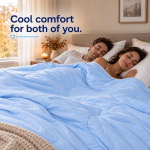 May include: A light blue quilted comforter featuring a circular stitched pattern. The text "Cool comfort for both of you." with a heart icon is visible in the upper left corner. The comforter is draped over two people sleeping in a bed.
