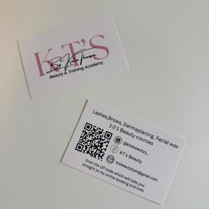 Può includere: Due biglietti da visita bianchi. Il biglietto superiore presenta il testo rosa "KT'S", con "By Katie Thomson" e "Beauty & Training Academy" in nero. Il biglietto inferiore elenca i servizi di bellezza, un codice QR e le informazioni di contatto.