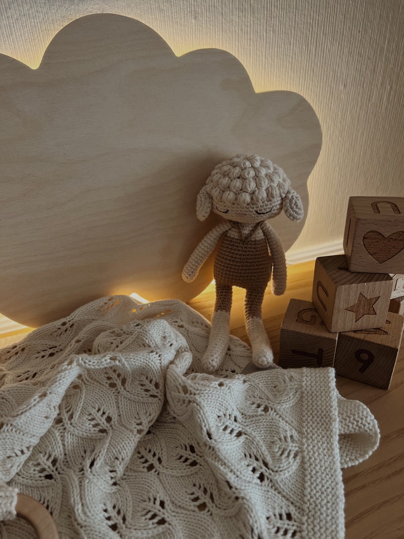May include: A white crocheted blanket with a delicate pattern, a crocheted lamb toy, and wooden blocks with numbers and a star design.