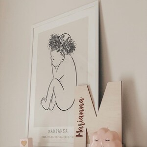 Pu&ograve; includere: Un disegno in bianco e nero di un bambino con una corona di fiori. Il disegno &egrave; su uno sfondo beige. La cornice &egrave; bianca. Il nome "Marianka" e la data "2016.10.03/01:50/4180G/59" sono stampati sotto il disegno. Una lettera in legno "M" con il nome "Marianna" inciso su di essa &egrave; appoggiata contro la cornice. Un oggetto rosa a forma di nuvola con un viso sorridente &egrave; davanti alla lettera. Un piccolo blocco di legno a forma di cuore &egrave; sullo scaffale sotto la cornice.