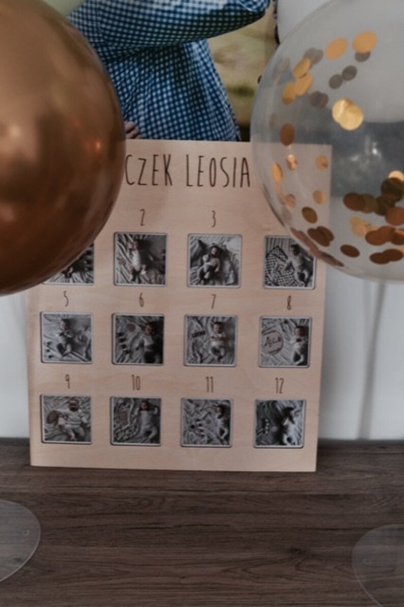 Może przedstawiać: Drewniana tablica z 12 oprawionymi zdjęciami dziecka. Tablica ma napis "CZĘK LEOSIA" u g&oacute;ry i numery od 1 do 12 pod zdjęciami.