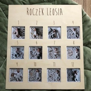 Może przedstawiać: Drewniana ramka na zdjęcia z 12 indywidualnymi ramkami na zdjęcia, każda z numerem od 1 do 12. Ramka ma napis "Roczek Leosia" u g&oacute;ry.
