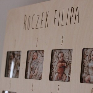 Może przedstawiać: Drewniany panel do wyświetlania zdjęć z napisem "ROCZEK FILIPA" na g&oacute;rze. Panel ma osiem kwadratowych otwor&oacute;w na zdjęcia, ponumerowanych od 1 do 8. Otwory są wypełnione zdjęciami małego chłopca w r&oacute;żnym wieku.