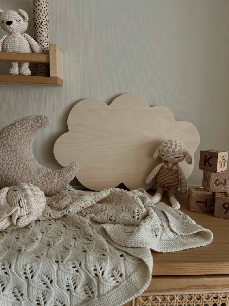 May include: A wooden cloud-shaped shelf with a crocheted lamb toy, a crocheted crescent moon toy, and a crocheted bear toy. There are also wooden blocks with letters and numbers on them.