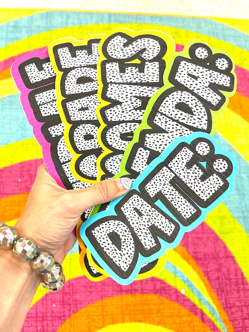 May include: Five colorful, polka-dotted paper signs with the words "Date", "Idea", "Games", "Inside", and "Fun" written in black.