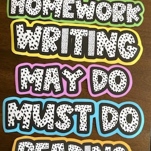 May include: Five colorful classroom signs with black and white polka dots. The signs read "Homework", "Writing", "May Do", "Must Do", and "Reading".