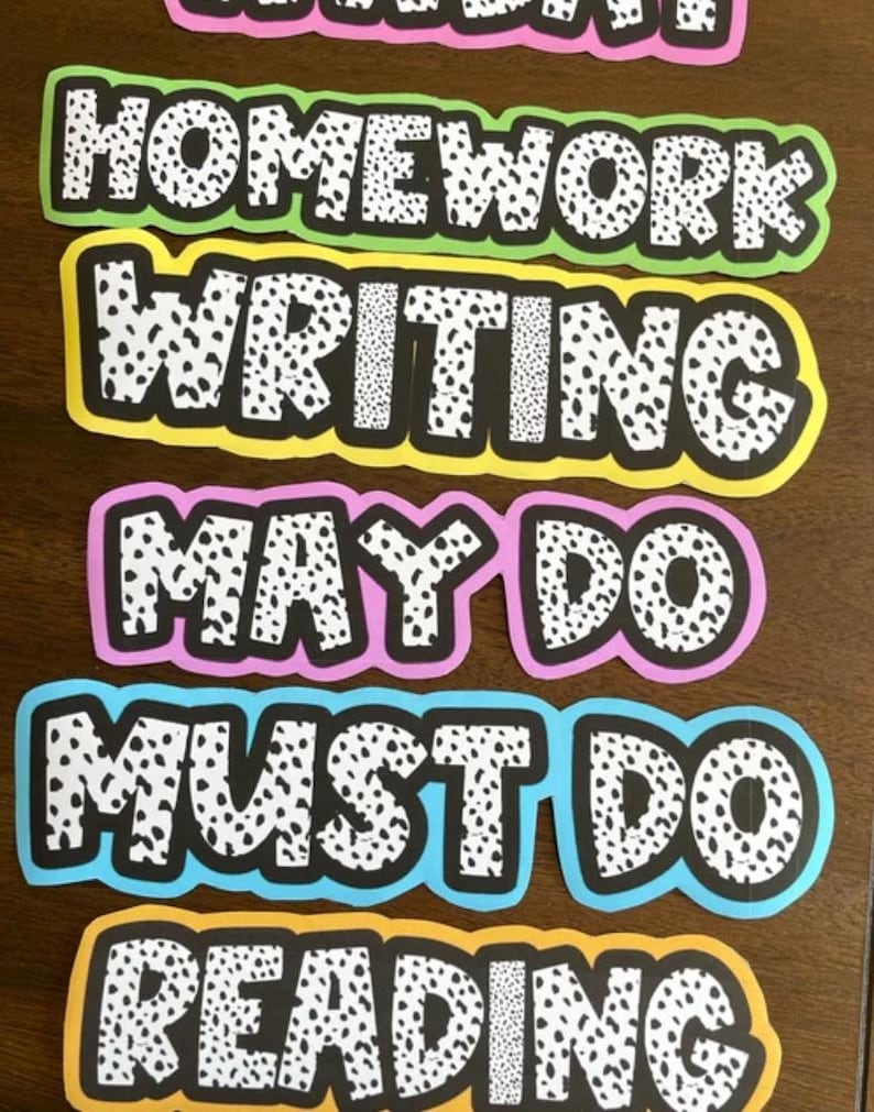 May include: Five colorful classroom signs with black and white polka dots. The signs read "Homework", "Writing", "May Do", "Must Do", and "Reading".