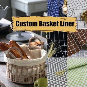 May include: A wicker basket with a white fabric liner, filled with bread loaves. The image also shows various fabric samples with different patterns, including gingham, plaid, and geometric designs. The text "Custom Basket Liner" is displayed in a yellow banner.