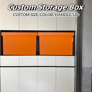 Op de afbeelding: Twee oranje opbergdozen staan in een witte en donkerbruine kast. De tekst "Custom Storage Box" en "CUSTOM SIZE/COLOR/HANDLE/LID" worden bovenaan de afbeelding weergegeven.