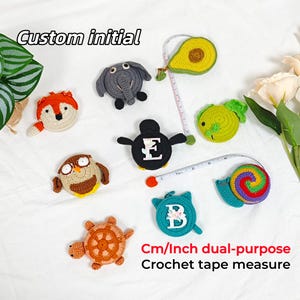Puede incluir: Una colección de cintas métricas de ganchillo con forma de animales, incluyendo un zorro, un elefante, un búho, una tortuga, un aguacate, un pez, un pingüino y un caracol. Cada cinta métrica tiene un diseño único y está etiquetada como "Custom initial" y "Cm/Inch dual-purpose Crochet tape measure".