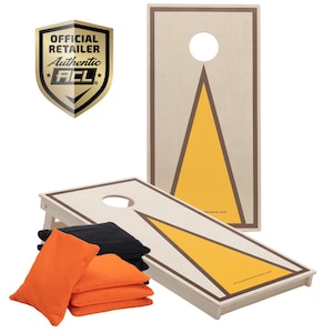 Könnte beinhalten: Zwei hölzerne Cornhole-Bretter mit einem gelben Dreiecksdesign und braunem Rahmen. Die Bretter sind für ein Spiel aufgebaut, mit orangefarbenen und schwarzen Bohnensäcken davor.