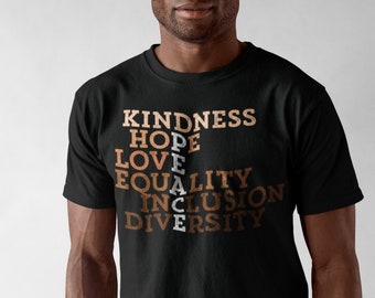 May include: A black t-shirt with the words "KINDNESS", "HOPE", "LOVE", "PEACE", "EQUALITY", "INCLUSION", and "DIVERSITY" printed in brown and white.