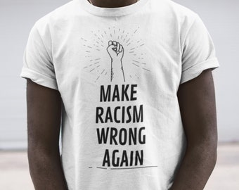 Puede incluir: Camiseta blanca con un puño negro levantado en el aire y el texto "MAKE RACISM WRONG AGAIN".