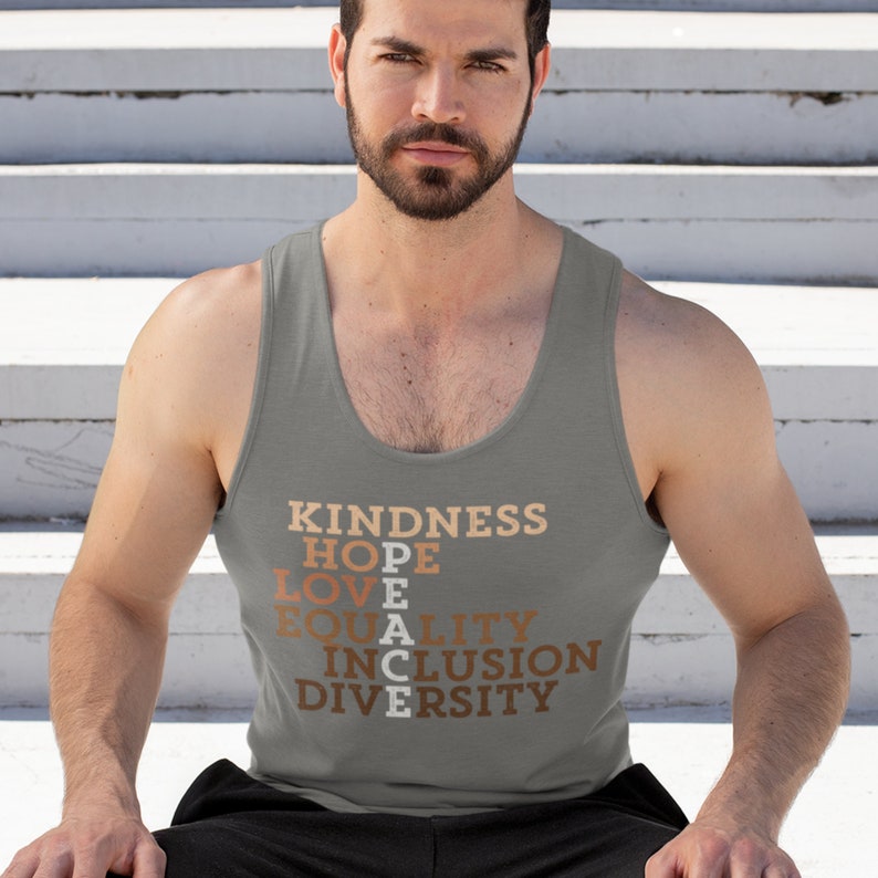 May include: A gray tank top with the words "KINDNESS", "HOPE", "LOVE", "PEACE", "EQUALITY", "INCLUSION", and "DIVERSITY" printed in brown and orange.