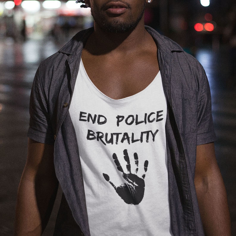 以下が含まれることがあります： 「END POLICE BRUTALITY」という文字と黒い手のひらのプリントがされた白いタンクトップ