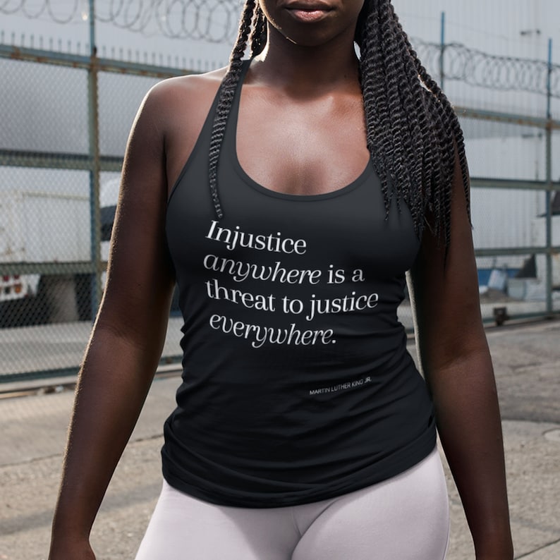 May include: Black racerback tank top with the quote "Injustice anywhere is a threat to justice everywhere." by Martin Luther King Jr. printed in white.