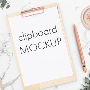 May include: A white clipboard with the text "clipboard MOCKUP" on a marble surface with a rose gold pen, a cup of coffee, and rose gold paper clips.