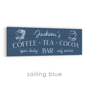 May include: A rectangular, sailing blue wooden sign with white text. The sign reads "Jackson's COFFEE &bull; TEA &bull; COCOA BAR open daily self service" with sketched coffee cup illustrations. The sign is designed for a coffee, tea, and cocoa bar.