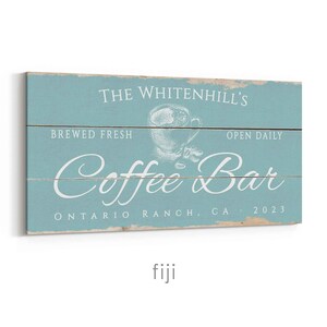 Pode incluir: Uma placa de madeira azul clara desgastada com as palavras "The Whitenhill's Coffee Bar" em escrita branca. A placa tamb&eacute;m inclui o texto "Brewed Fresh", "Open Daily" e "Ontario Ranch, CA 2023". Um gr&aacute;fico de x&iacute;cara de caf&eacute; est&aacute; no centro.
