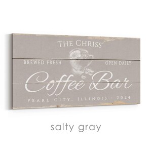 Pode incluir: Uma placa retangular de madeira cinza com texto branco que diz "THE CHRISS' Coffee Bar" com "BREWED FRESH" e "OPEN DAILY" acima e um gr&aacute;fico de x&iacute;cara de caf&eacute;. A placa tamb&eacute;m diz "PEARL CITY, ILLINOIS 2024".