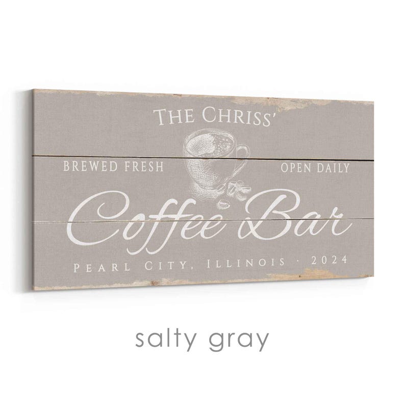 Pode incluir: Uma placa retangular de madeira cinza com texto branco que diz "THE CHRISS' Coffee Bar" com "BREWED FRESH" e "OPEN DAILY" acima e um gr&aacute;fico de x&iacute;cara de caf&eacute;. A placa tamb&eacute;m diz "PEARL CITY, ILLINOIS 2024".