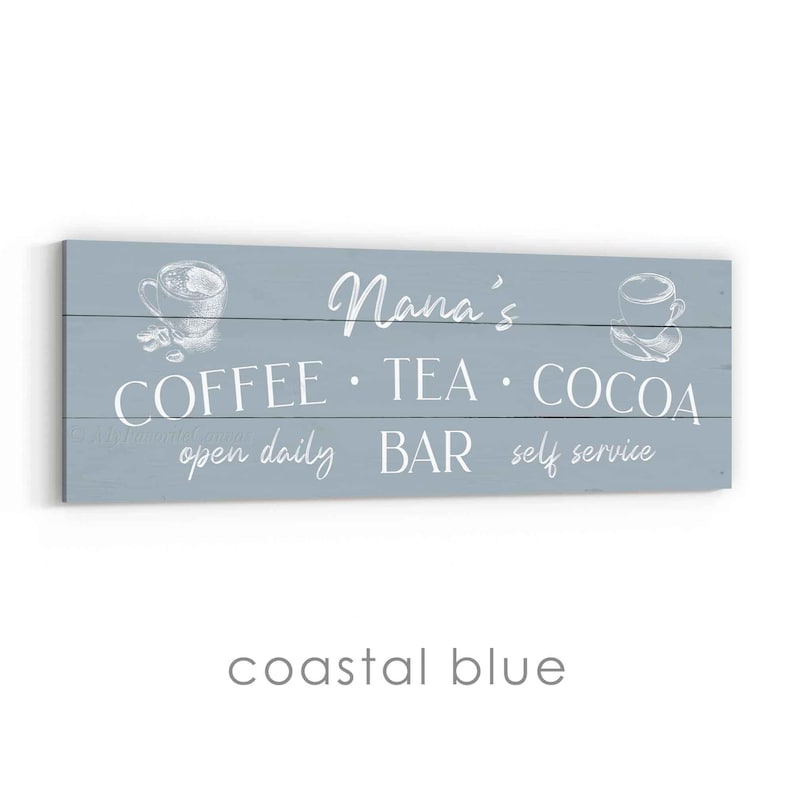 May include: A coastal blue wooden sign with white text. The sign reads "Nana's COFFEE &bull; TEA &bull; COCOA open daily BAR self service." It features illustrations of coffee cups.