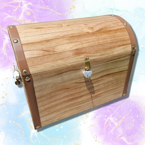 May include: A wooden treasure chest with a curved top and brown leather trim. The chest has a brass clasp and a heart-shaped lock with a key. The wood grain is visible, and the chest is secured with metal studs.