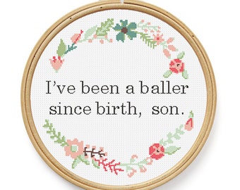 May include: A white embroidery hoop with a floral wreath design and the text "I've been a baller since birth, son."