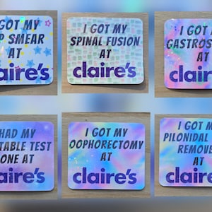 May include: A collection of six rectangular stickers with holographic backgrounds and text. Each sticker has a different phrase, such as "I GOT MY PAP SMEAR AT claire's". The stickers have a colorful, glittery design.