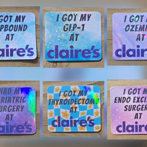 May include: A collection of six square stickers with holographic and pastel backgrounds. Each sticker has the phrase "I GOT MY" followed by a medical term and "AT claire's". The stickers are in shades of blue, purple, and pink.