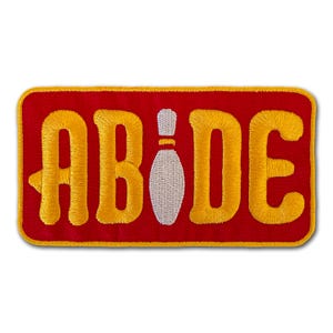 May include: Red and yellow embroidered patch with the word "ABIDE" and a white bowling pin in the center.