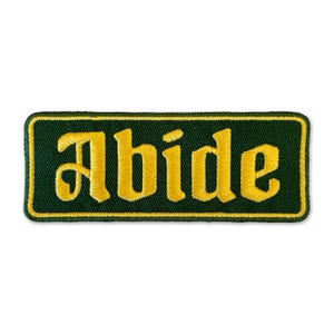 May include: A green and yellow embroidered patch with the word "Abide" in a stylized font.