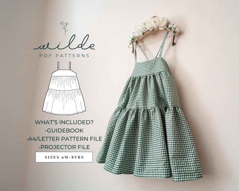 May include: A green and white gingham tiered dress with straps. The dress is hanging on a hanger with a floral crown on top. The text "wilde PDF PATTERNS" is at the top of the image. The text "WHAT'S INCLUDED? -GUIDEBOOK -A4/LETTER PATTERN FILE -PROJECTOR FILE SIZES 9M-8YRS" is at the bottom of the image.